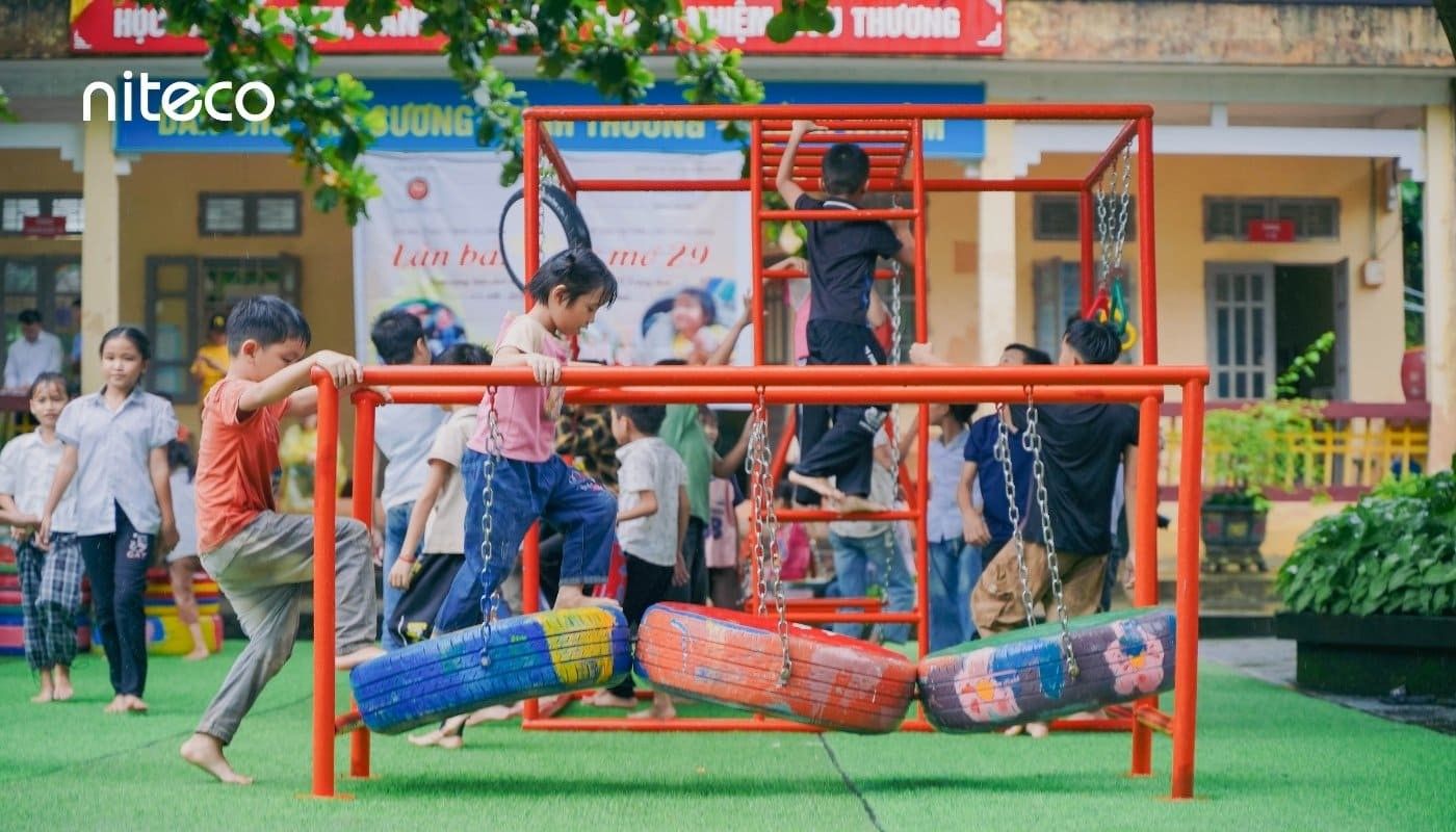 Children playing on colorful tire swings and climbing frames at school playground