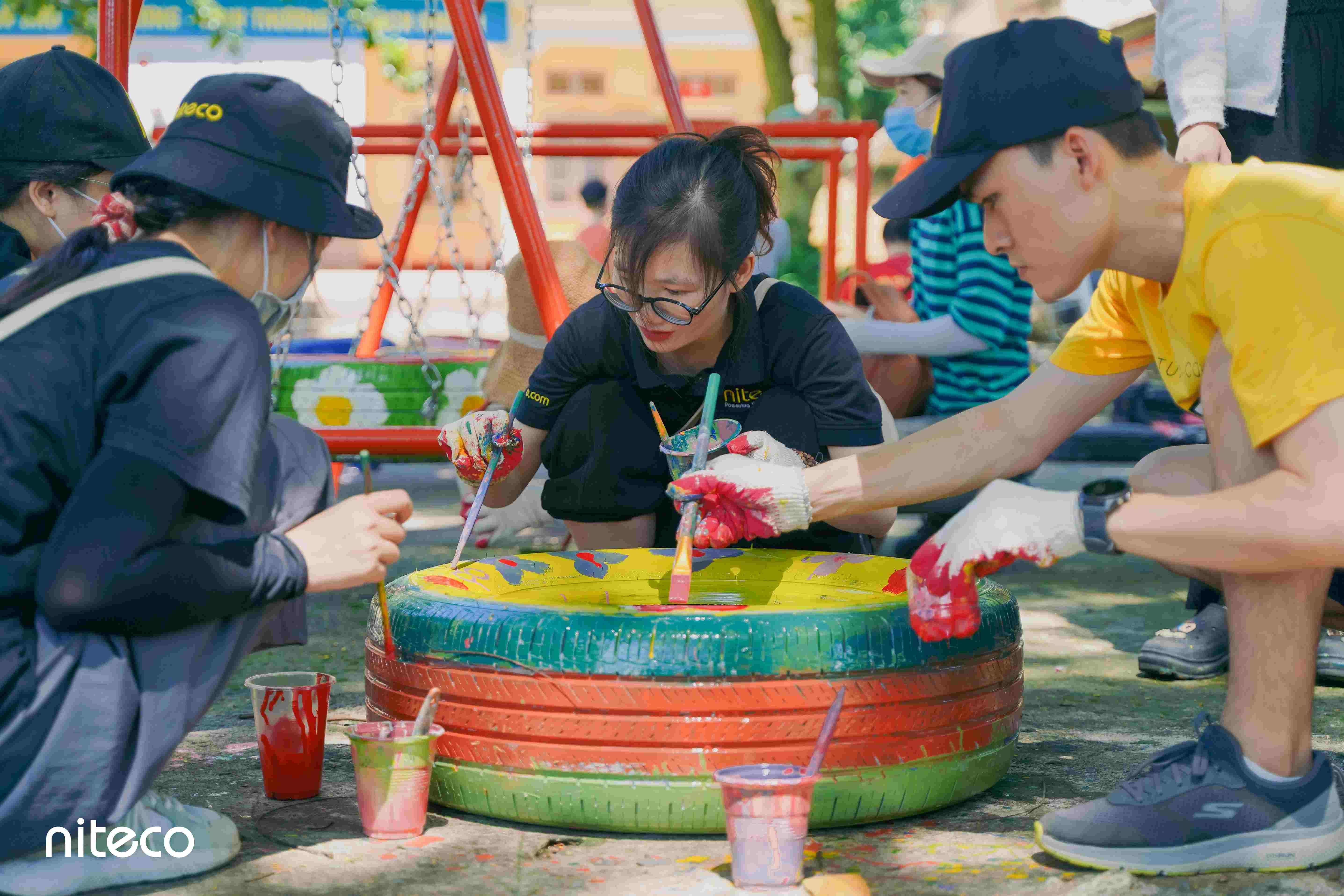 Volunteers painting recycled tires for playground improvement with bright colors