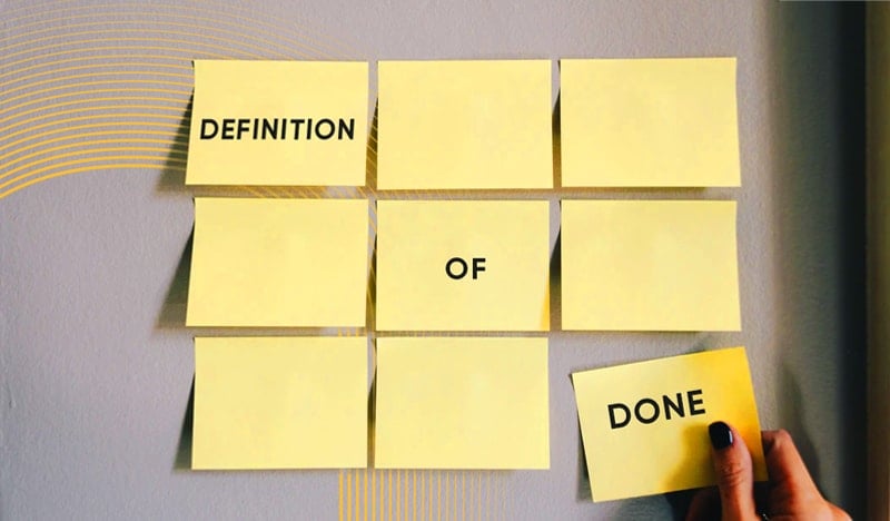 Yellow sticky notes arranged to spell "Definition of Done" on gray wall