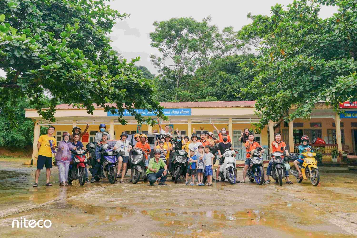 Group gathered with motorbikes outside a building, Niteco team event