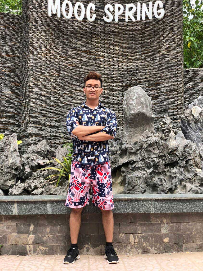 Young man standing confidently at MOOC Spring pavilion with nature background