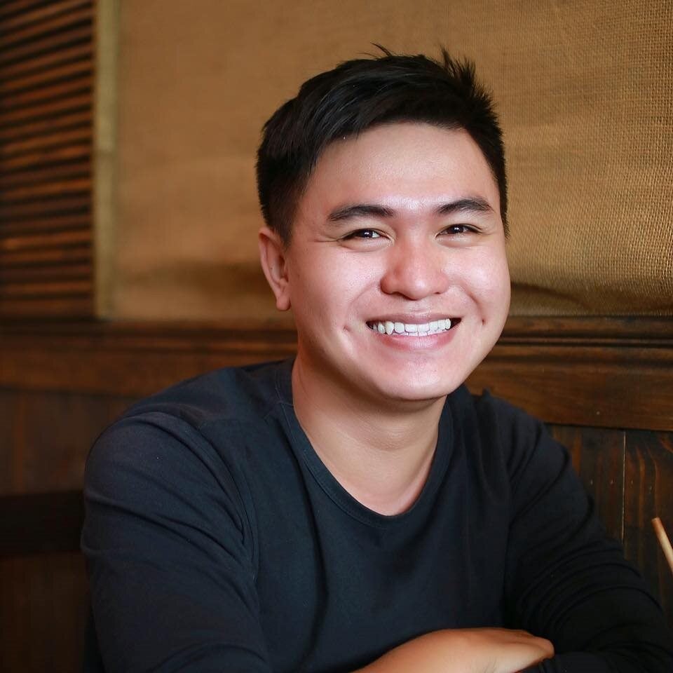 Happy young man wearing black shirt smiling indoors at cafe