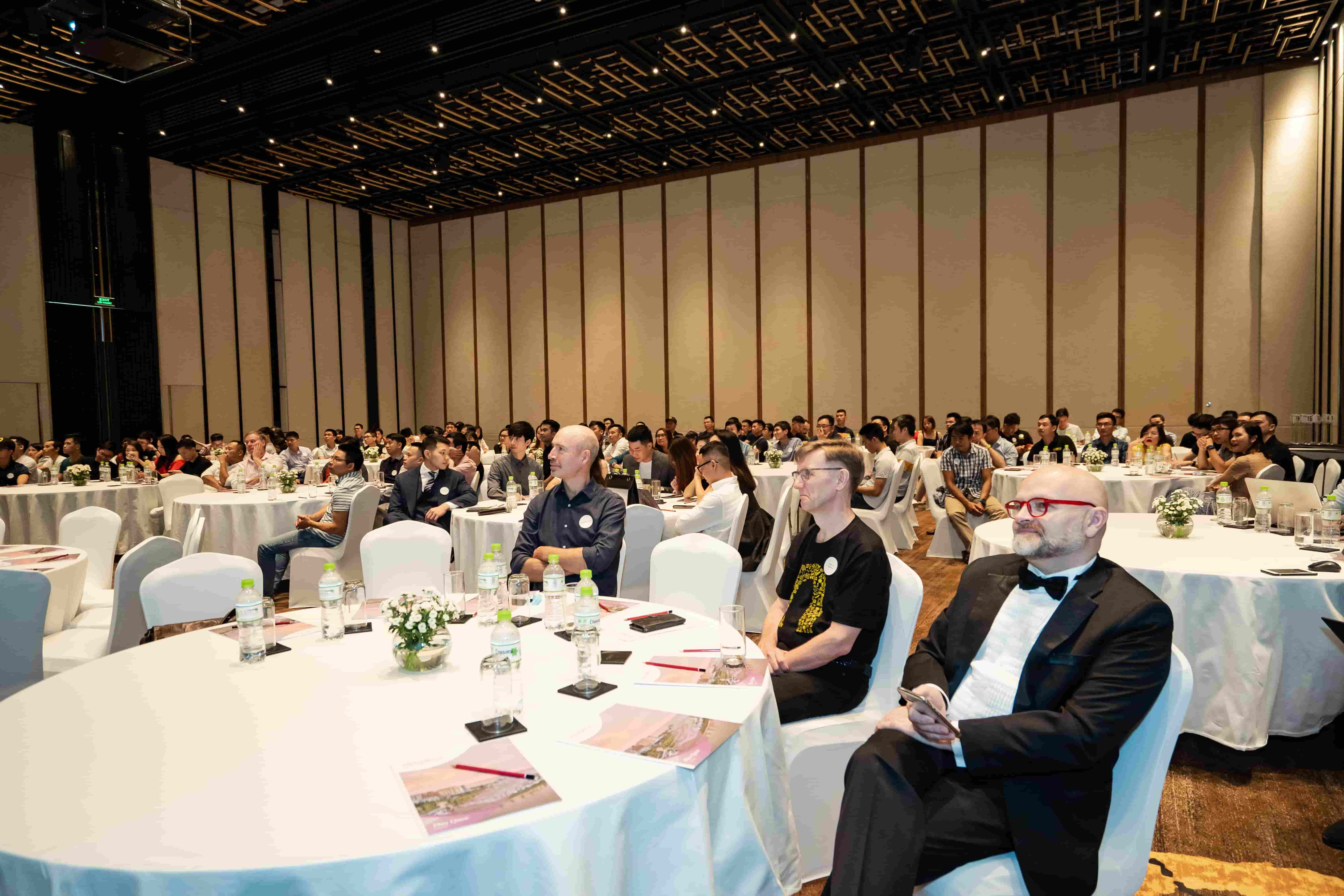 Conference attendees seated at round tables listening to keynote speakers