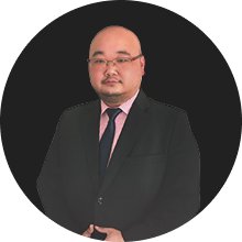 Professional businessman in black suit with pink tie against dark background