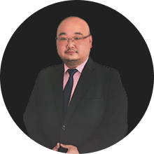 Professional businessman in black suit with pink tie against dark background