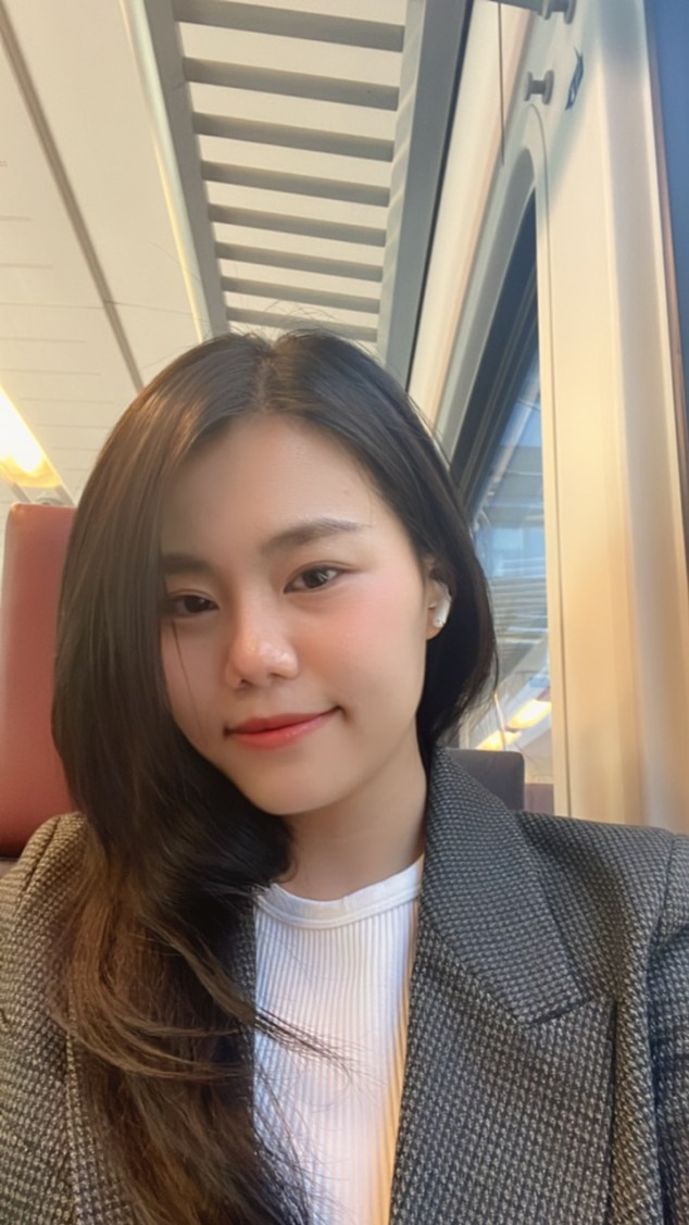 Young woman with long hair wearing a gray blazer on a train journey