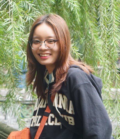Smiling young woman with glasses wearing Carolina Polo Club hoodie outdoors