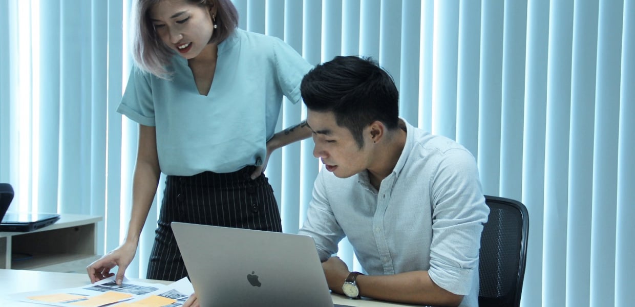 Young professionals collaborating on office documents with laptop and charts