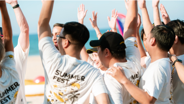 corevalue Group of friends celebrating and raising hands at a summer fest on the beach