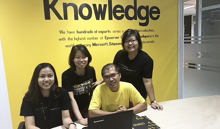 Team collaborating in front of a yellow Knowledge wall with laptop and notebooks