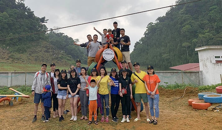 Group of people enjoying outdoor team building event at green mountainside
