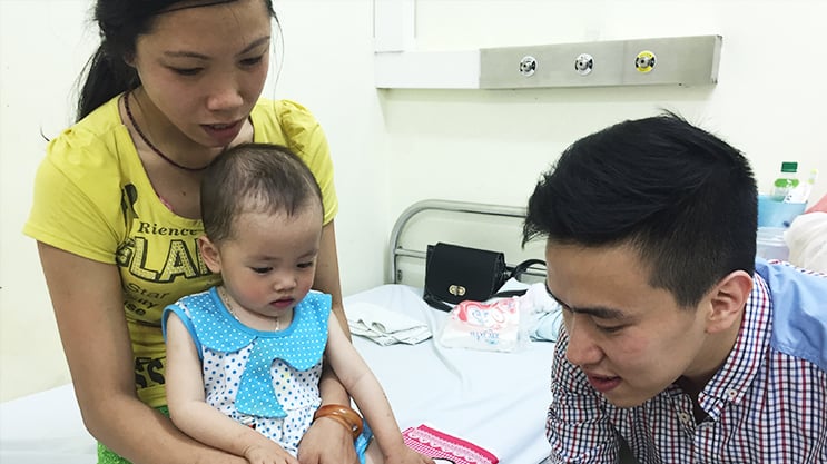 Mother and father caring for toddler girl in hospital pediatric care room