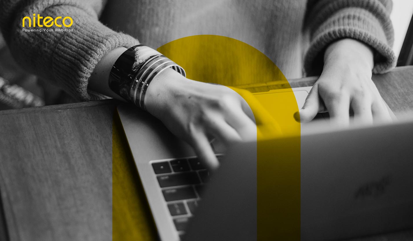 Hands typing on laptop keyboard with Niteco logo and yellow accent design