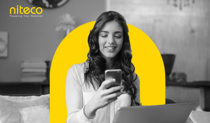 Young woman using smartphone and laptop with Niteco branding and tagline