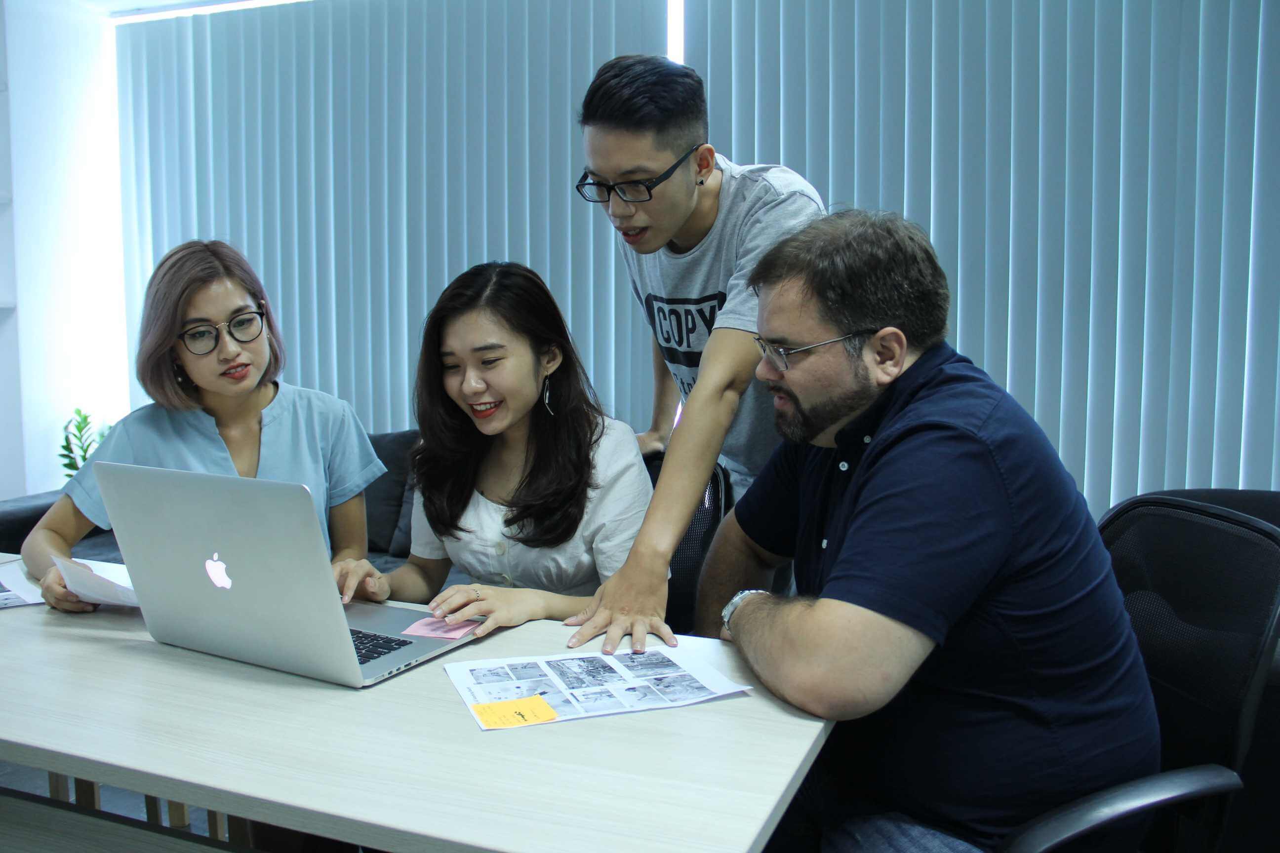 Team collaborating on digital marketing strategy using laptop and printouts