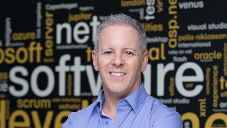 Man in blue shirt smiling with software development and .net keywords background