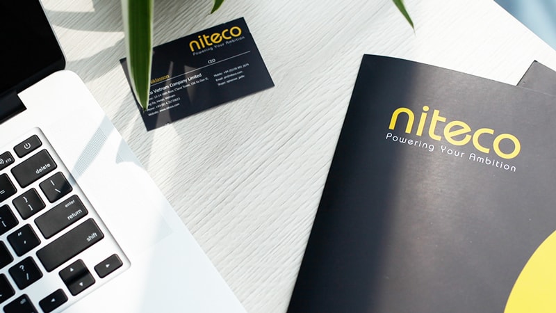 Niteco branded business card and brochure on a white office desk near laptop